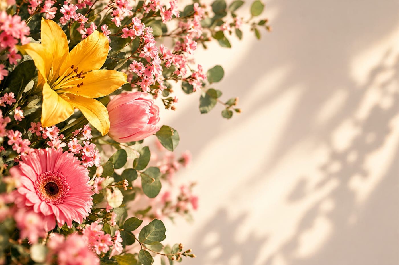 Arranjo de lírio amarelo, tulipa e gérberas cor-de-rosa com folhas de eucalipto, sob a luz da tarde